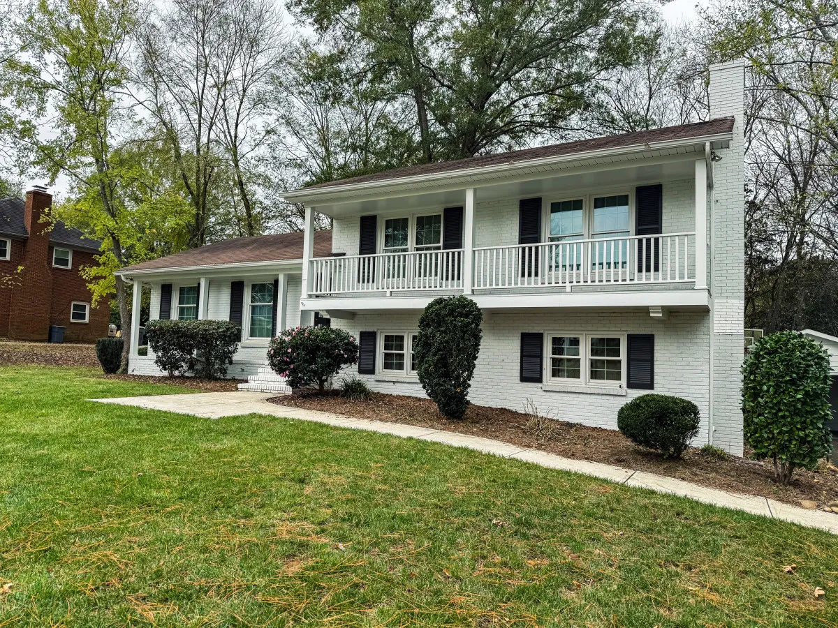 A view of the home's front porch with neatly trimmed bushes and a welcoming two-story facade. This inviting exterior sets the scene for a friendly, safe neighborhood and hints at relaxing mornings or evenings spent outdoors.